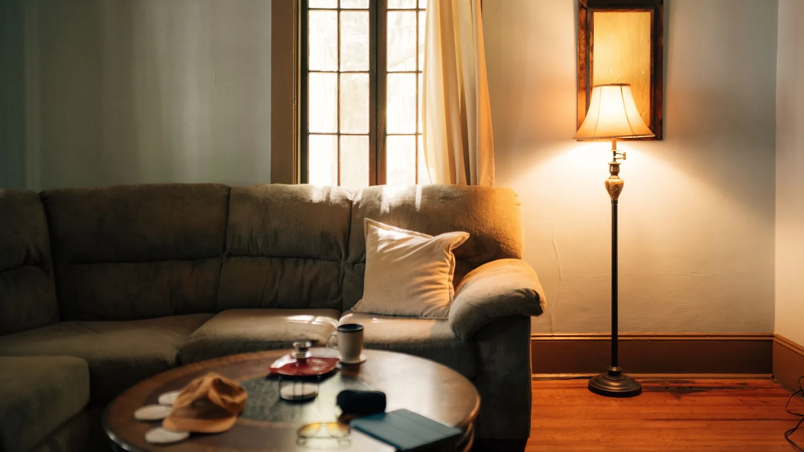 A warm, naturally lit modern living room with a soft sofa and floor lamp